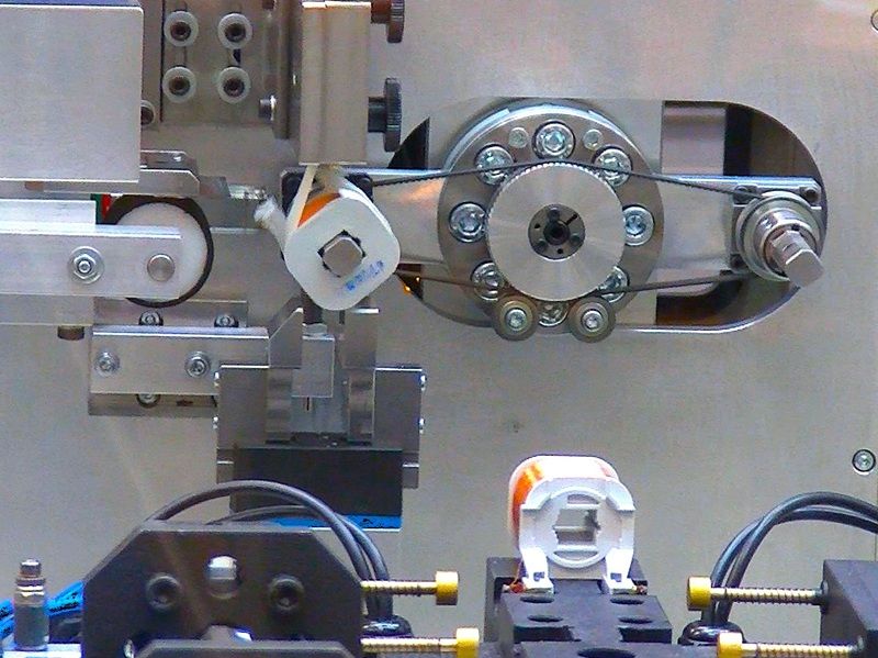 ULR - Zrobotyzowane stanowisko produkcyjne od NEOTECH www.neotech.pl/maszyny/ Automatyczne Gniazdo Wykończeniowe, Zrobotyzowane stanowisko produkcyjne Strefa pracy robota SCARA, podajników, topnikowania, cynowania i pomiaru Czteroosiowy robot SCARA Yamaha z chwytakiem pneumatycznym i silnikiem obrotowym na stanowisku roboczym ULR Stacja cynowania wysokotemperaturowego: Stacja cynowania cewek ULR z tyglem o pojemności 6400 g i mocy 1200 W, generującym temperaturę lutowania do 600 stopni Celsjusza Stacja taśmowania uzwojeń, wrapping: Moduł automatycznego taśmowania uzwojeń cewki z chwytakiem taśmy izolacyjnej, prowadnicą z regulacją szerokości oraz nożem tnącym. Stacja pomiaru elektrycznego, strefa QC: Stacja kontroli jakości cewek ze sprzęgami pomiarowymi sterowanymi pneumatycznie, zintegrowana z testerem elektrycznym Szafa sterownicza i pneumatyczna: Otwarta szafa sterownicza maszyny ULR-02 z zainstalowanym sterownikiem przemysłowym Omron PLC, modułami bezpieczeństwa i wyspą zaworową Panel operatorski HMI, ekran główny: Ekran dotykowy panelu HMI NEOTECH do obsługi, edycji parametrów technologicznych i diagnostyki pracy zrobotyzowanej maszyny ULR-02 W bezpiecznej, zamkniętej obudowie ochronnej z kolumną sygnalizacyjną i panelem HMI